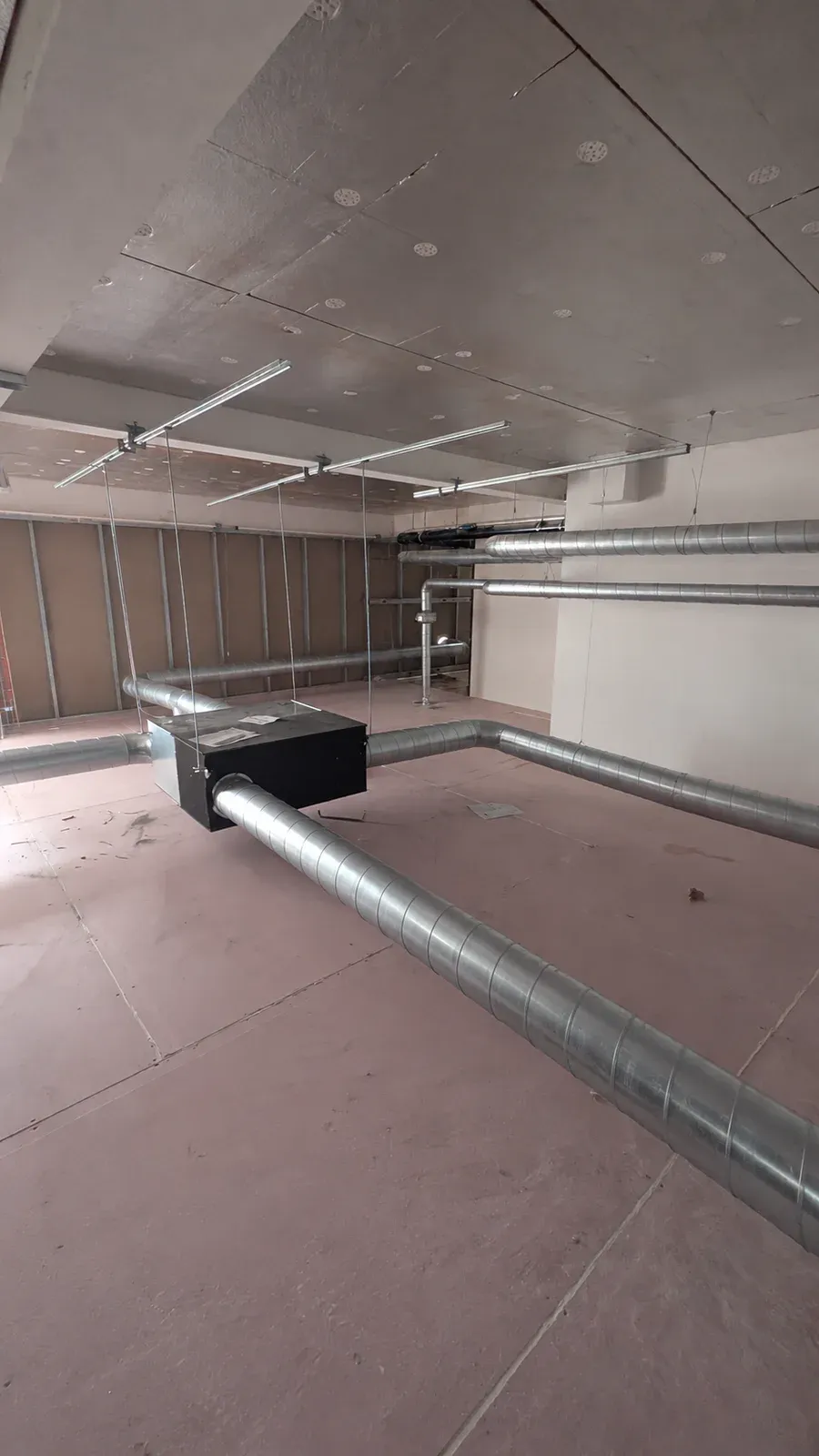 Suspended mechanical ventilation unit connected to metal ductwork during installation