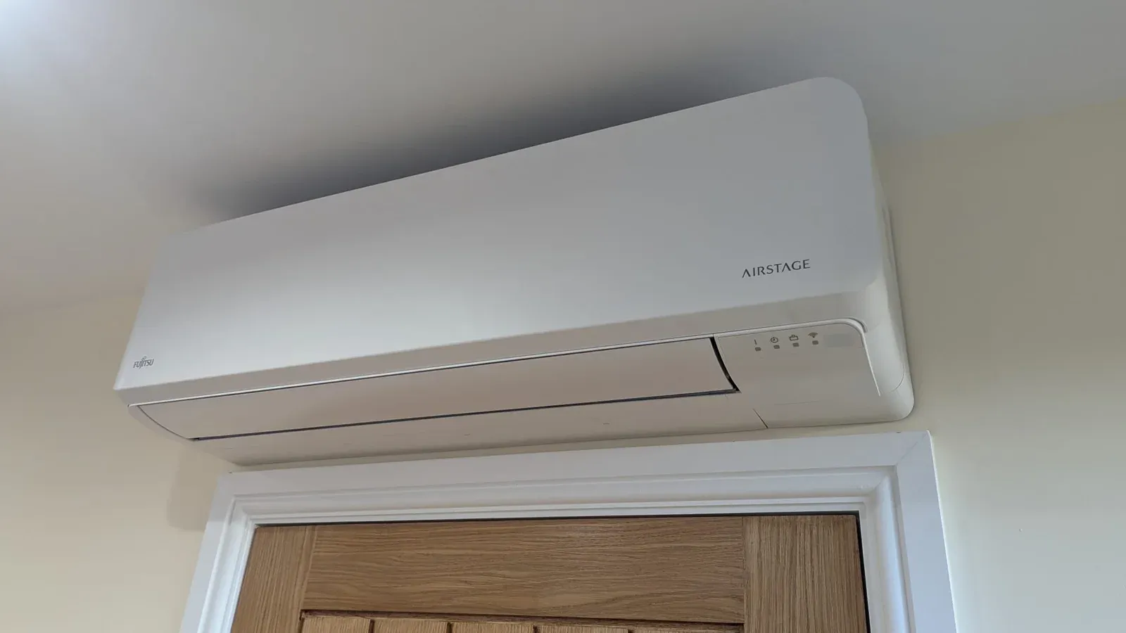 Wall-mounted indoor air conditioning unit installed above a doorway